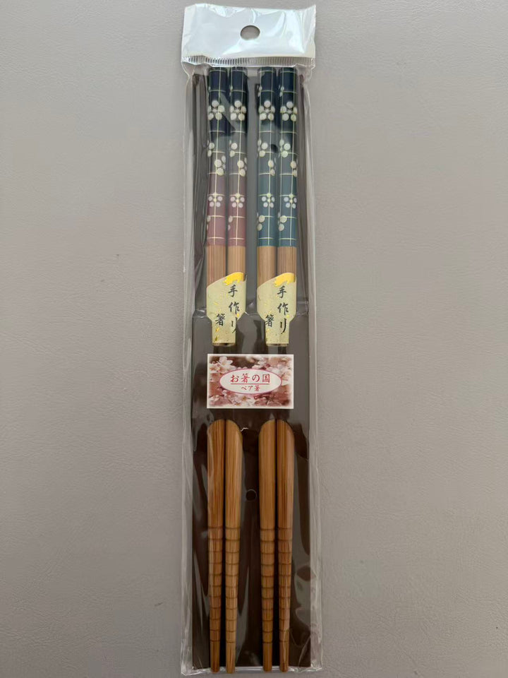 Two pairs of bamboo chopsticks with plum blossom designs in original packaging
